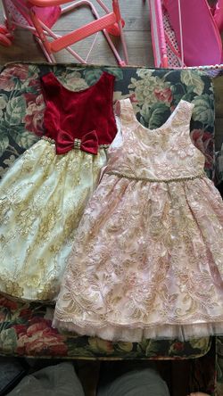 Beautiful set of two girls formal dresses. One dress has a red velvet top with a gold embroidered skirt and a red bow with a rhinestone buckle. The ot