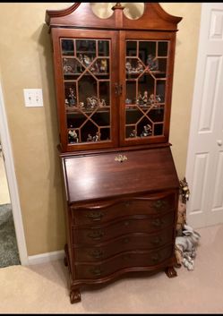 vintage mahogany secretary desk featuring a glass-paneled upper hutch and a drop-front writing surface.