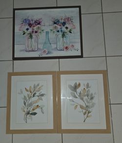 Three framed watercolor style art prints. 1 mason jar floral print 27”x21”, 2 pair leaf prints each 18”x22”. Frames in good condition, glass clean, re