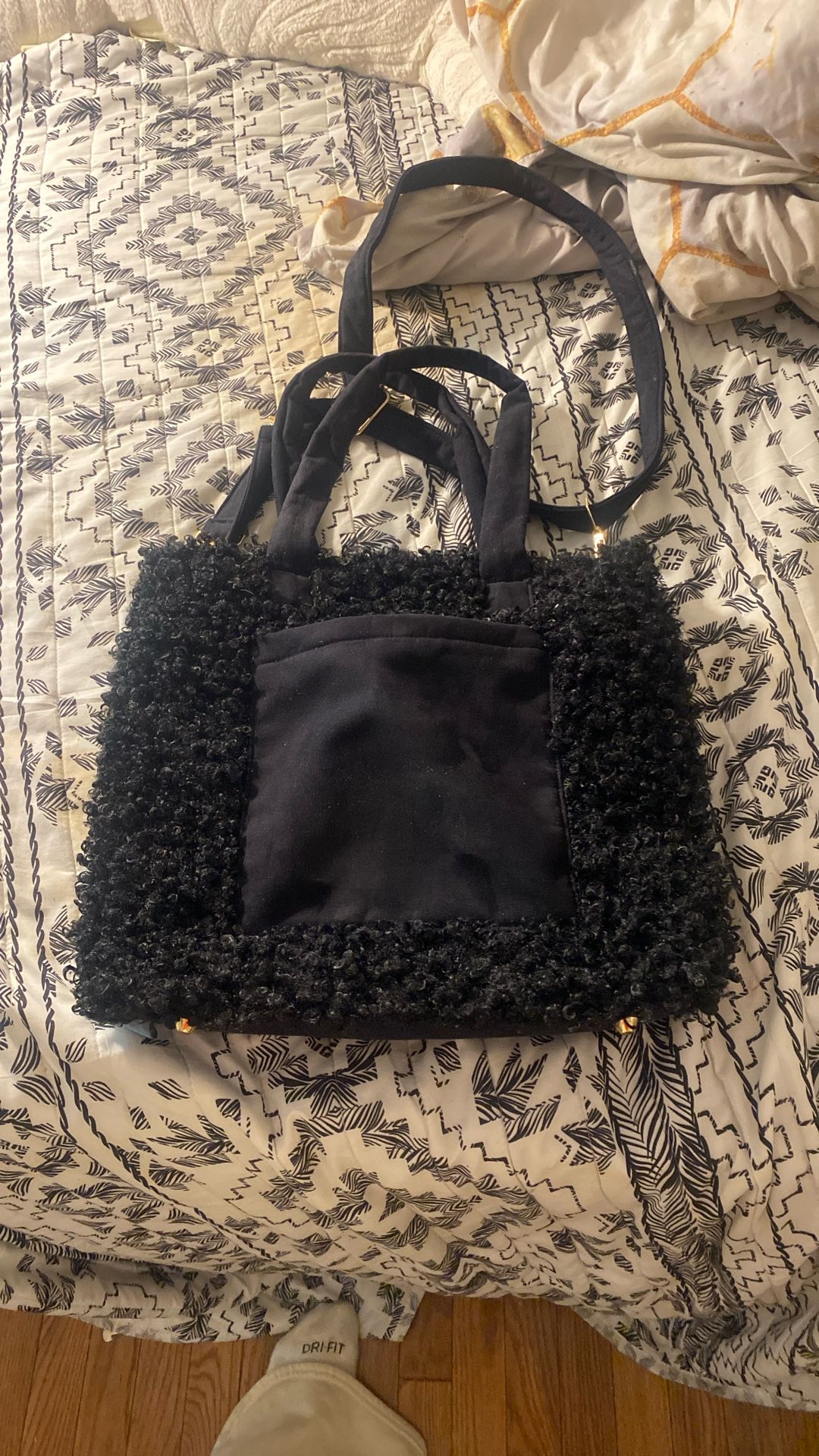 This is a black curly faux fur tote bag with a laptop sleeve.