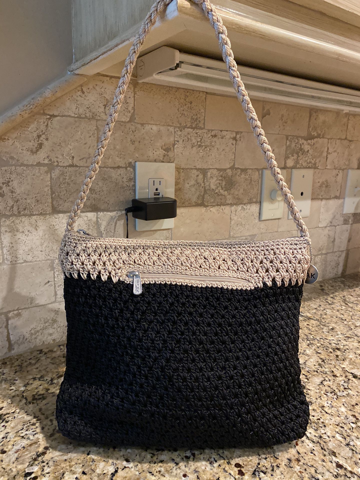 The SAK Purse with zipper closure. Has zipper pocket inside and outside (9 1/2” L x 12” W). The strap is 11” from zipper closure. Black & Taupe