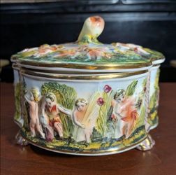 Vintage Capodimonte style porcelain hand-painted footed trinket box made in Italy, featuring a high-relief cherub/putti  garden scene