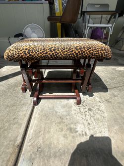 Comfortable wooden glider ottoman featuring a soft leopard-print upholstered cushion and a smooth gliding motion. Perfect as a footrest for a nursery