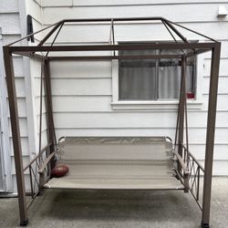 Brown Metal Swing With Canopy Frame And Beige Seat. 