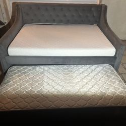 BONITA CAMA FULL SZ TAPIZADA DE GRIS CON TRUNDLE BED ABAJO CON COLCHONES FULL Y TWIN SZ USADA BUENA CONDICIÓN 