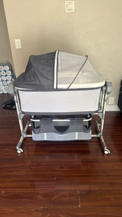 Gray and white crib, automatic rocking with settings, soft music, remote control included, storage under crib, movable.