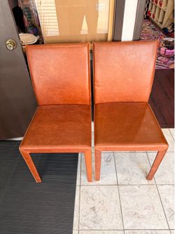 Pottery Barn genuine leather dining chairs in a burnt orange color.