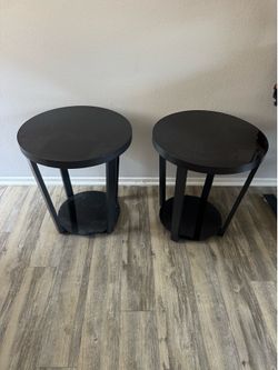 Set of 2 modern tempered glass end tables with black metal frames.