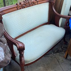 This is a French Louis XV style settee or loveseat with a carved wooden frame and light-colored upholstery.  