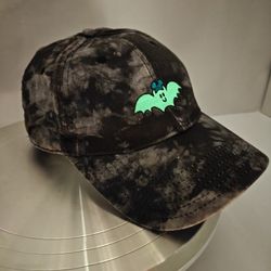 Disney Parks tie-dye style baseball cap features an embroidered glow-in-the-dark bat wearing Mickey Mouse ears