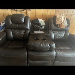 Brown Leather Couch With Ports And Desk In Middle 