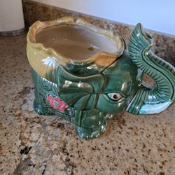 This is a vintage green ceramic elephant planter with a lucky trunk up design. 