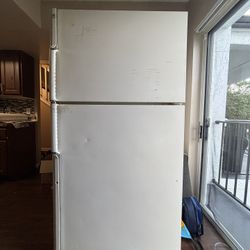 White GE refrigerator with top freezer. 