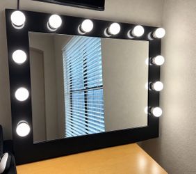 Black Hollywood-style vanity mirror with bright globe bulbs around the frame. • *