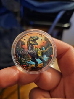 colorized 1 oz copper round featuring a detailed T-Rex design, protected within a clear capsule.