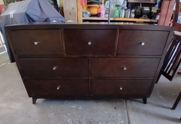 multi-drawer wood dresser in a dark