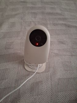 The item pictured is the Nooie Indoor Cam 1080p, a compact, budget-friendly smart security camera typically used for home monitoring, pet checking, or