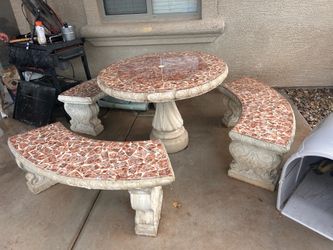 This concrete patio set typically features a round table and curved benches with a mosaic tile design.