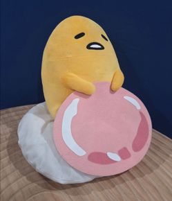 Sanrio Gudetama 15" Plush holding a slice of ham over an egg white cushion