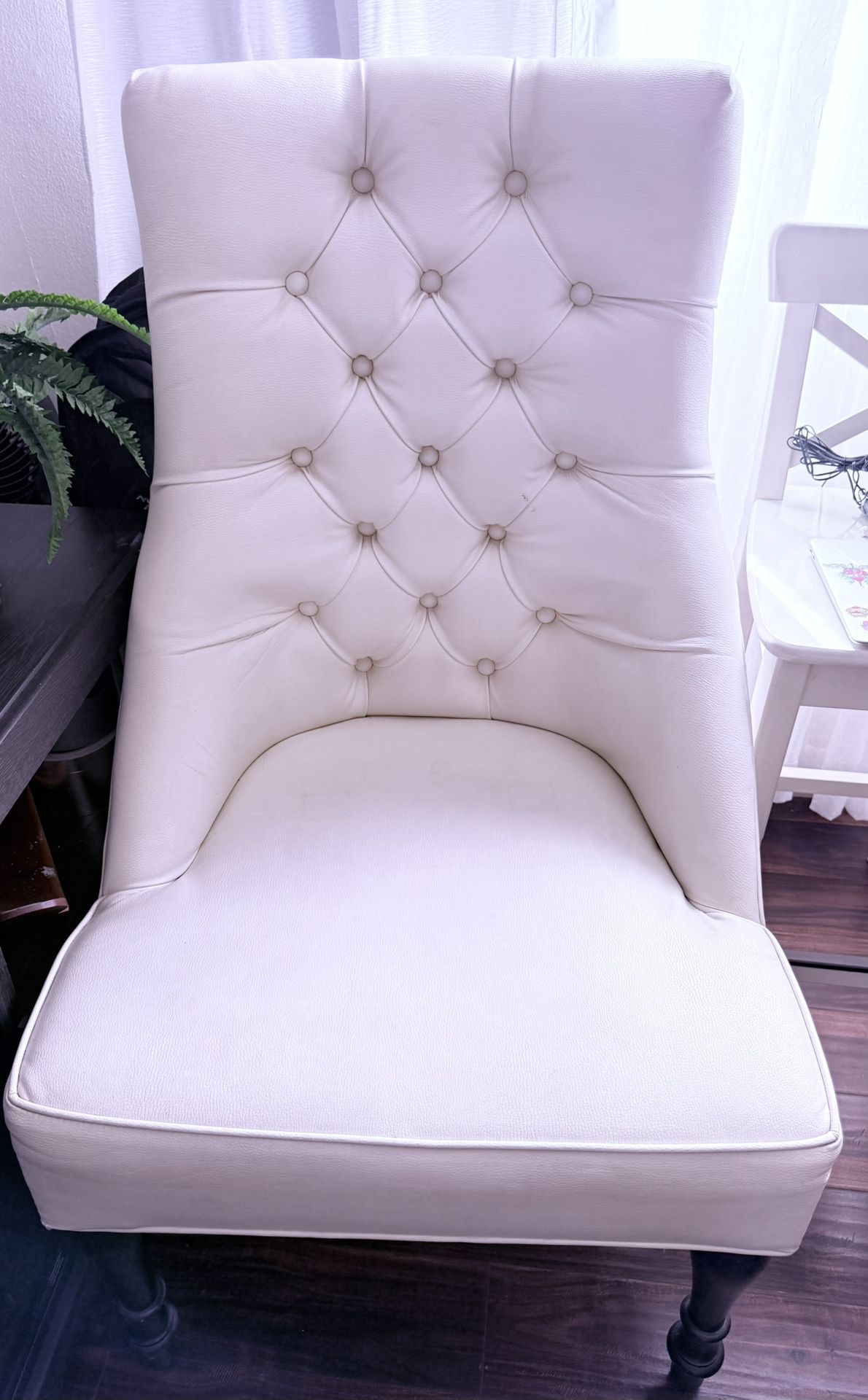 White leather upholstered chair with tufted detailing,