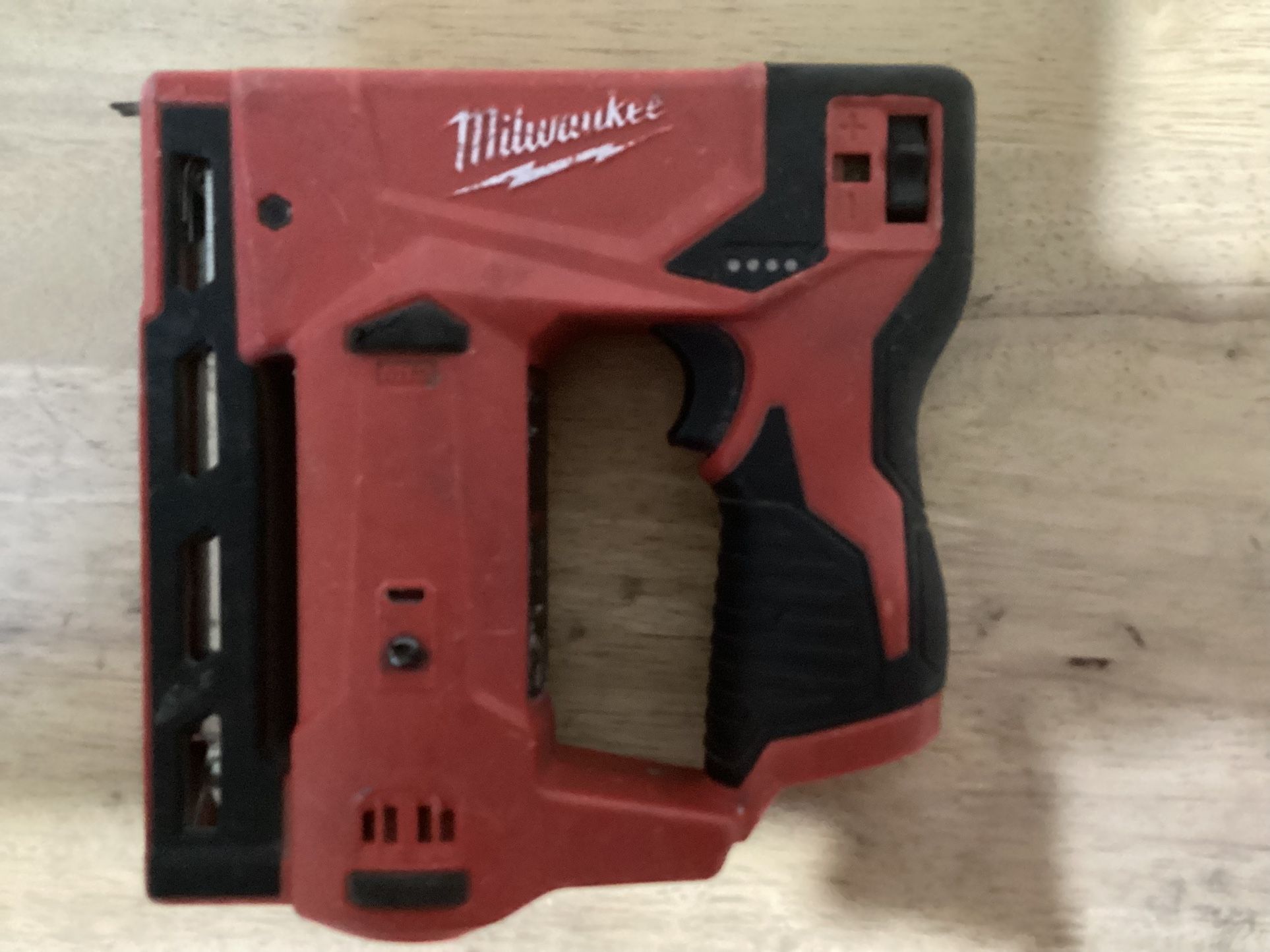 The tool shown is the Milwaukee M12 3/8" Crown Stapler, model number 2447-20
