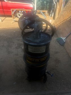heavy-duty portable oil container, closely resembling a used oil drum or waste oil transfer setup equipped with a pump and hoses.