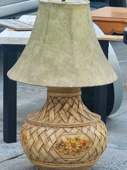 vintage woven rattan and wicker table lamp featuring a painted floral medallion and a textured parch