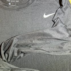 black Nike long-sleeve training shirt from the "THE NIKE TEE" collection, featuring Dri-FIT technology for moisture management