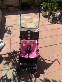 Disney Minnie Mouse umbrella stroller featuring a pink polka-dot seat and a black top design
