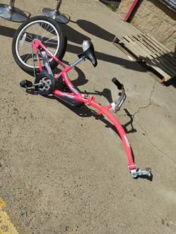 Pink WeeRide Co-Pilot tag-along bike features a quick-release system for fast detachment from an adult bicycle