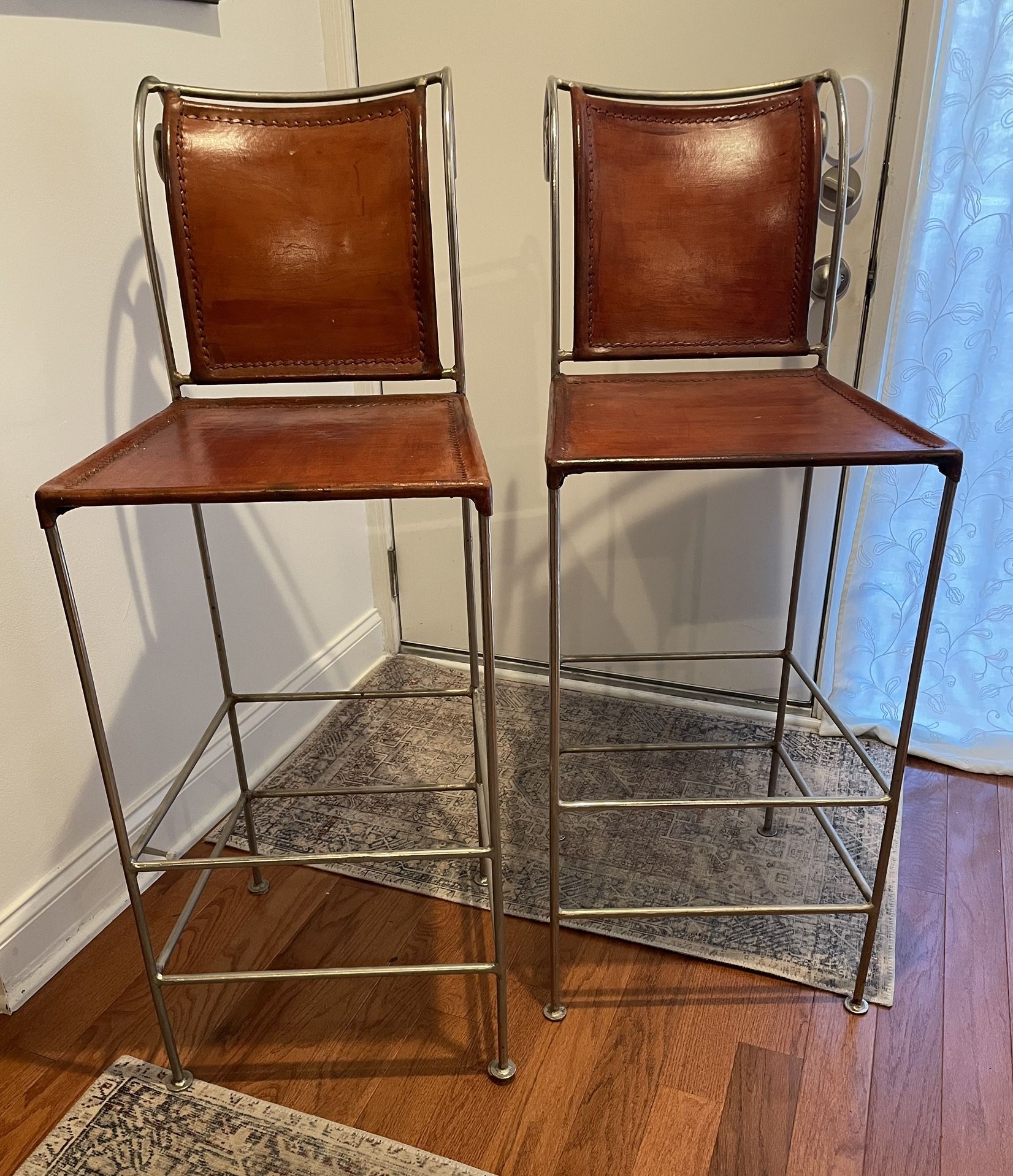 Two Vintage Spanish-style Cognac Leather Bar Stools with wrought iron scroll back.
