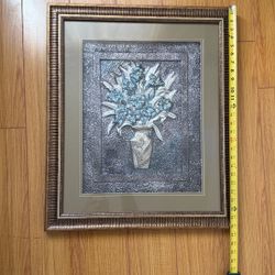 Decorative embossed metal wall art piece (often aluminum, pewter-toned metal, or mixed-media relief art) featuring a floral arrangement in a vase.