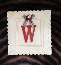 Monogram plaque with red capital letter "W” accented with a gingham fabric  black-and-white checkered bow.