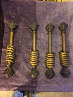 These are ornate antique gold-finished wooden drapery pole sets complete with matching decorative finials and stacked curtain rings.
