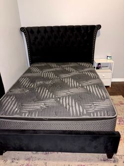 Black upholstered wingback full size bed frame with matching mattress.