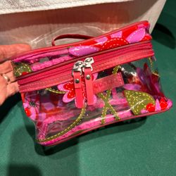 This travel Make Up bag is made of see-thru durable plastic or vinyl material with a pretty flowered design. It has a zippered top, a pouch on the