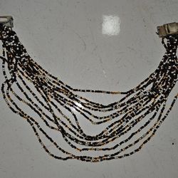 Bead necklace, black and gold colour, cylinders and spheres.