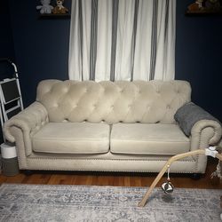 Cream colored couch (sofa) with nail trim and tufted back