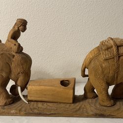 Vintage hand-carved wooden sculpture featuring two elephants with riders (mahouts) pulling a central rectangular box or container on a shared base.