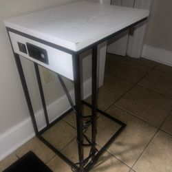 White C-shape end table with power/USB outlets. 
