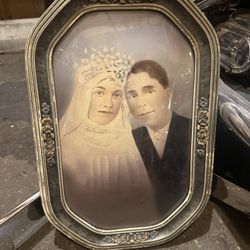  a vintage framed portrait of a couple in wedding attire, likely featuring a convex bubble glass cover within an ornate, oval-shaped frame