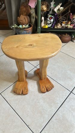 Wooden footstool with legs and feet.