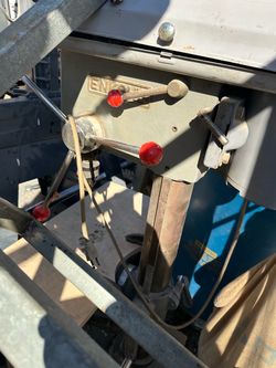 Heavy-duty Enkoh drill press is made of cast iron and steel. It has a gray finish with red handle knobs. This benchtop model includes an adjustable wo