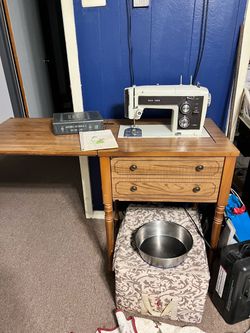 vintage Sears Kenmore sewing machine set into a wooden drop-leaf sewing cabinet,