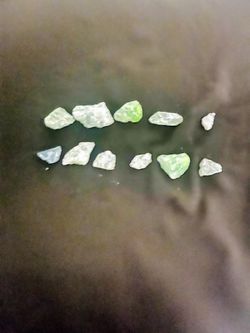 Natural rough emerald crystal stones come in a set of eleven pieces. This collection has light green and translucent white specimens with raw, unpolis