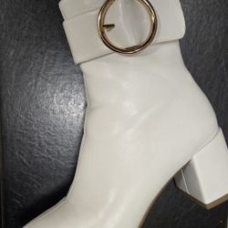 white ankle boots with a prominent gold-toned chain