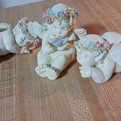 3 LITTLE CHERUBS/ANGELS, NO CHIPS OR CRACKS, 2 LYING DOWN ARE 4 1/2" L EA. 1 SITTING UP IS 4 1/2" H