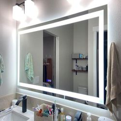 New LED bathroom mirror with integrated lighting and touch-sensitive controls. This rectangular mirror has a frosted light border and includes icons f