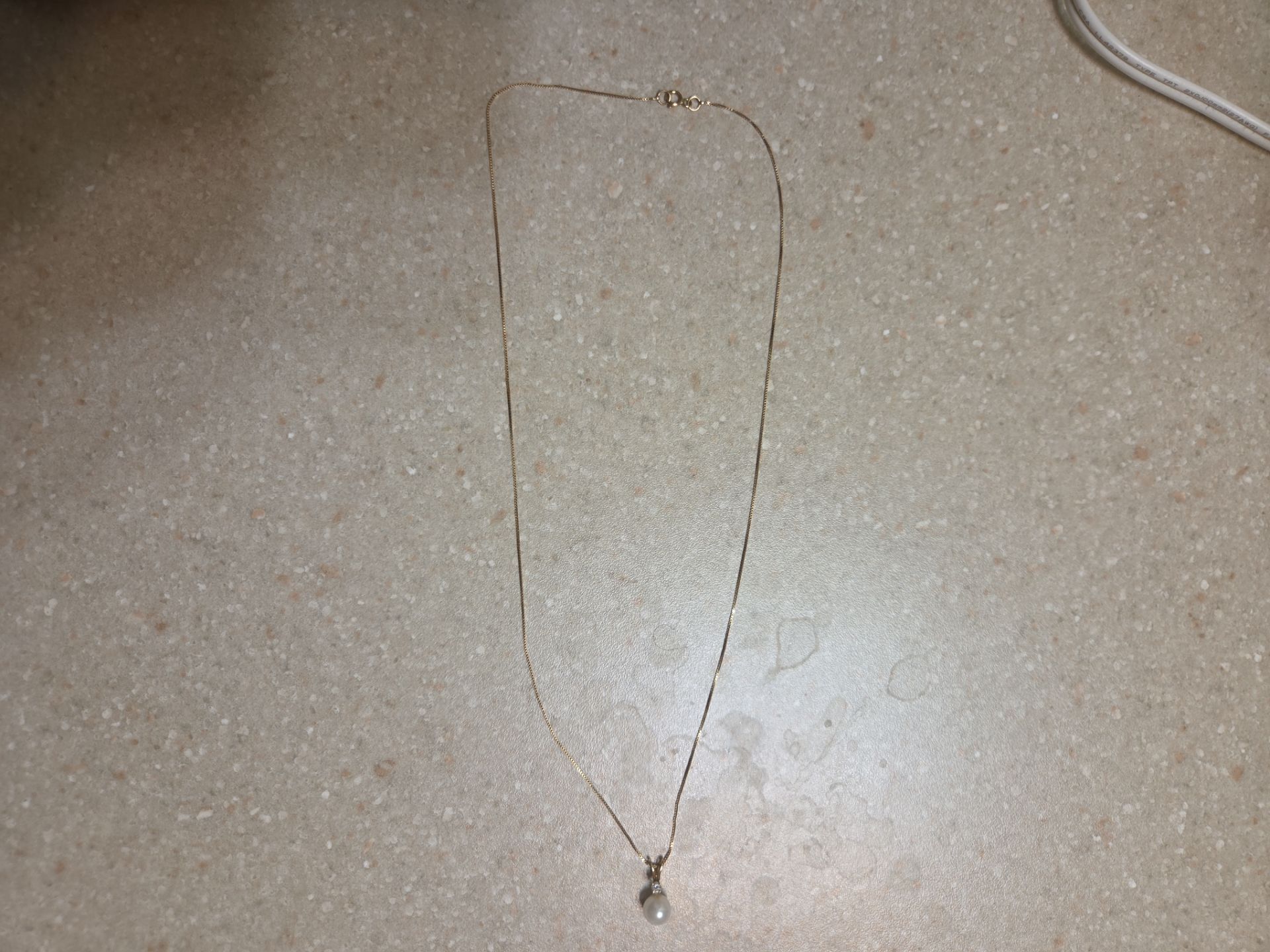 14 k gold necklace with 14 k gold pearl and diamond pendant. Weight is 1.7 grams