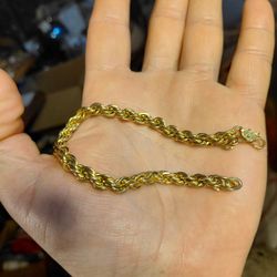  is a gold-toned rope chain bracelet with a lobster clasp. 